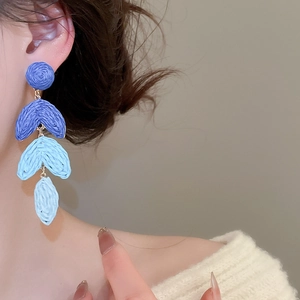 Detail of blue gradient raffia tassel earrings on model for bohemian beach style