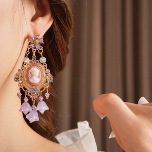Detail of vintage gold tassel earring with pink cameo and purple crystal beads on model
