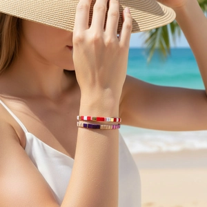 Detail of colorful Tila bead bracelets on wrist with a sunny beach holiday backdrop