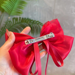 Detailed back view of a red pearlescent bow hair clip showing the metal alligator attachment