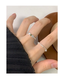 Detail of silver S925 bow ring featuring a green gemstone on woman's finger