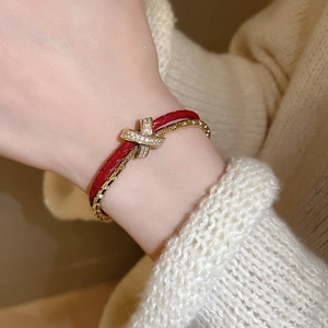 Détail du bracelet en cordon rouge tressé et fermoir croisé doré serti de zircons fins