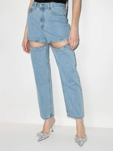 Détail de jean bleu clair à taille haute avec découpes ornées de cristaux sur la cuisse