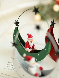 Macro shot of metal moon cradle with Santa figure on vintage book background