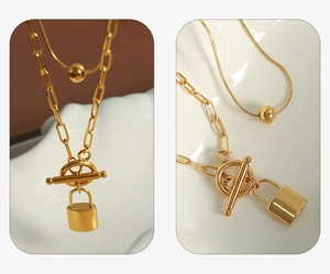 Detail of layered gold necklace featuring OT buckle, lock pendant and paperclip chain