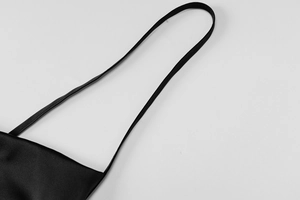Détail de la fine bretelle et du tissu satiné noir lisse sur une robe en dentelle chic