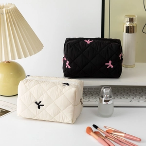 Close-up of quilted cotton cosmetic bags with embroidered bow details and zippers