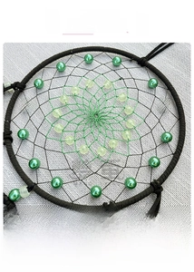 Detail of hand-woven dream catcher with luminous beads and green mesh grid pattern