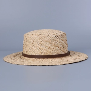 Detailed view of natural raffia boater hat weaving texture with slim brown leather band