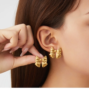 Detail of vintage gold bow earrings featuring a textured metallic finish and 3D ribbon design