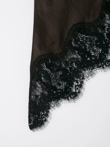 Detailed close-up of black lace and brown satin stitching on the irregular dress
