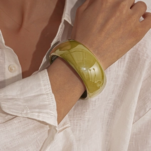 Detailed view of olive green acrylic wide bangle with high-gloss finish on a model