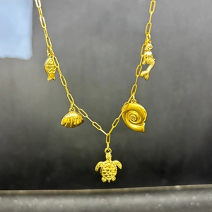 Detailed view of golden marine charms with mermaid and turtle on a stainless steel chain