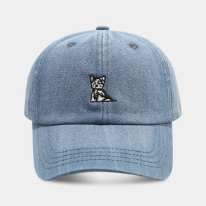 Close-up of fine embroidery showing a small dog on washed blue denim baseball cap
