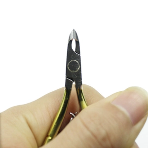 Detail showing hand holding gold and silver nail cuticle nipper for manicure care