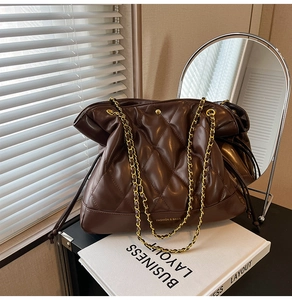 Detail of dark brown quilted leather bucket bag with gold chain strap and fashion logo