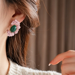 Close-up of vintage flower earrings with pink petals and green oval gemstone on model