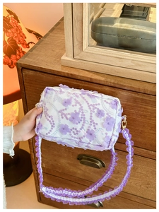 Detailed close-up of floral crossbody bag with purple sequins and ruffled strap