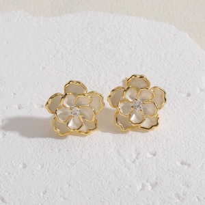 Macro shot of camellia flower stud earrings with gold plating and white enamel finish