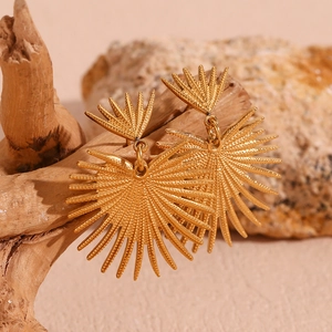 Detailed view of bohemian 18K gold plated fan-shaped earrings on natural rock background