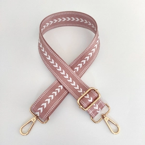 Detailed view of pink nylon strap with white arrow patterns and gold metal clasps