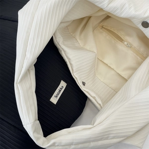 Gros plan sur la texture côtelée blanche, la doublure en toile et le fermoir de ce sac fourre-tout