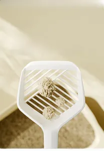 Close-up of white cat litter shovel with diagonal grid for efficient waste sifting