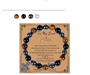 Detail von 10mm Tigerauge- und Obsidianperlen mit Kreuzanhänger auf einer Geschenkkarte