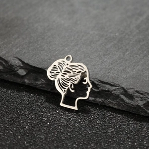 Macro detail of silver stainless steel cutout female silhouette pendant on a stone surface
