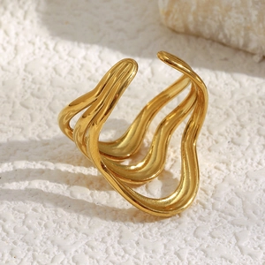 Close-up of golden three-layer wave ring on white stone with warm natural lighting