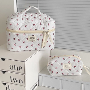 Macro view of quilted cherry pattern makeup bag showing soft cotton texture and zipper