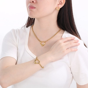 Gold hollow heart jewelry set featuring necklace, bracelet and earrings on model