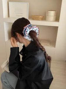 Detail of blue plaid hairband with cherry print and white lace on braided brown hair