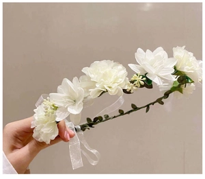 Detail of white bridal flower crown with silk petals, green leaves, and sheer ribbon