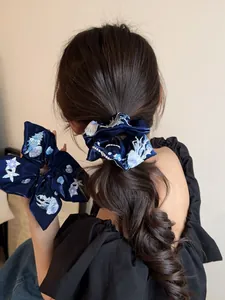 Detail of dark blue velvet scrunchie featuring intricate sea life embroidery and bow