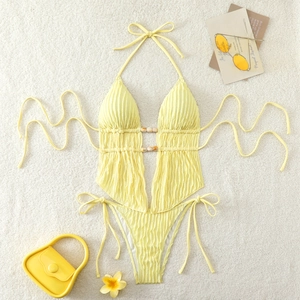 Flat lay of yellow monokini with ribbed texture, hollow out design and wooden beads