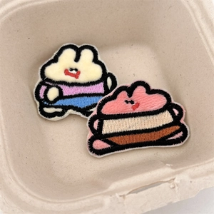 Detailed close-up of cute cartoon plush embroidery pins for bags and clothing decoration