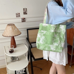 Dettaglio della borsa tote in tela tie-dye verde con tasca esterna ed etichetta del marchio
