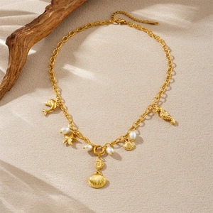 Gold ocean themed necklace with starfish seahorse and shell pendants on sand