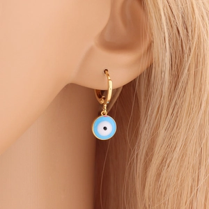 Close-up of a gold teardrop earring with blue Evil Eye charm worn on ear