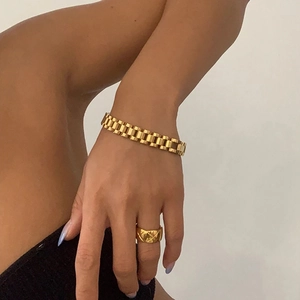 Detailed view of adjustable golden metal watch-style link bracelet and quilted gold ring