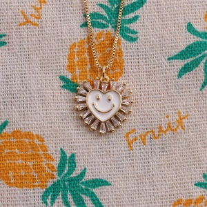 Gros plan du pendentif cœur doré avec visage souriant et zircons étincelants