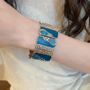 Detail of bohemian wide stretch bracelet with blue enamel waves and silver textured metal