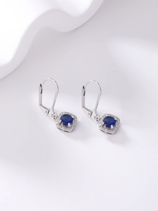 Detailed macro view of silver earrings featuring a square deep blue zircon stone