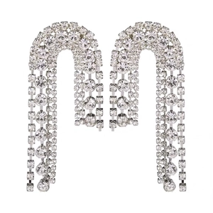 Silver U-shaped tassel earrings with asymmetrical rhinestones on a white background