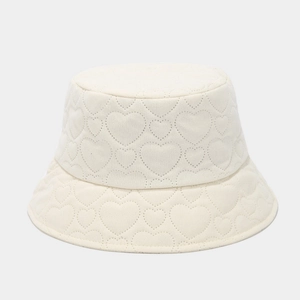Close-up of heart-shaped quilted pattern on cream corduroy bucket hat texture