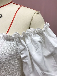 Detail of off-shoulder white floral dress with smocked bodice and ruffled neckline trim