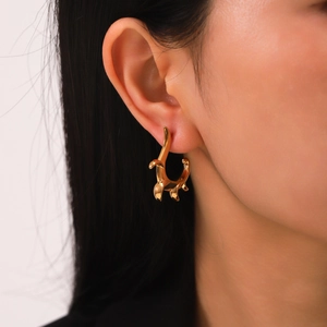 Close-up of irregular C-shaped 18K gold plated stainless steel stud earring on ear