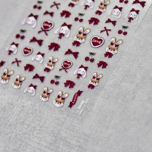 Macro detail of embossed nail stickers featuring cartoon rabbits, hearts, and red bows