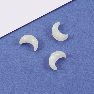 White synthetic resin opal moon charms with holographic glitter on blue background